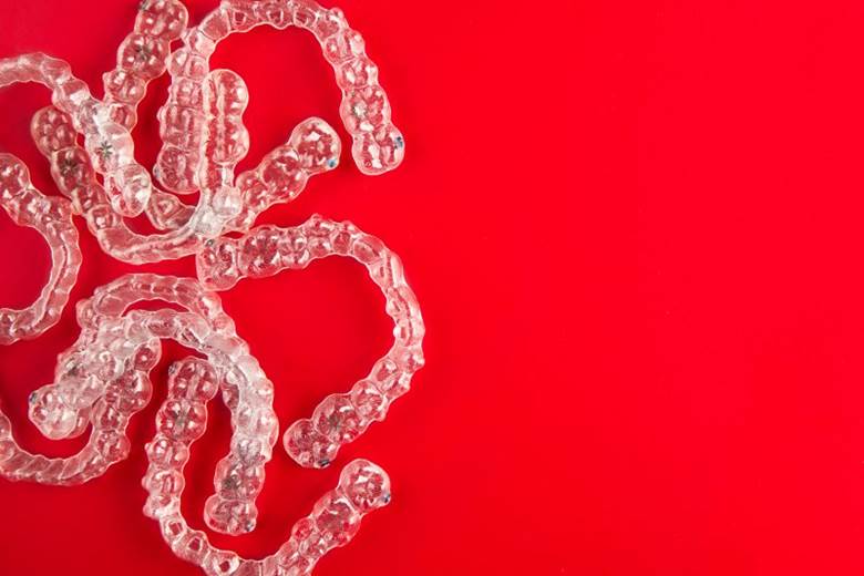 several clear aligners in front of a red background