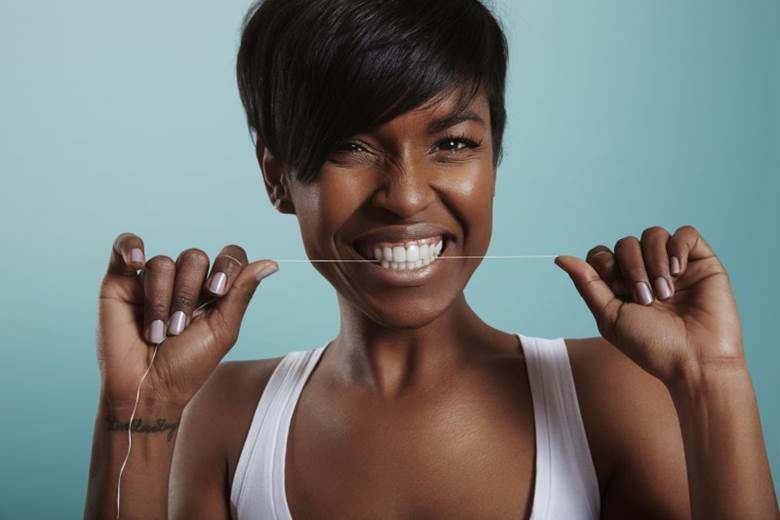 Woman flossing after in-office ZOOM! teeth whitening in Edmonton